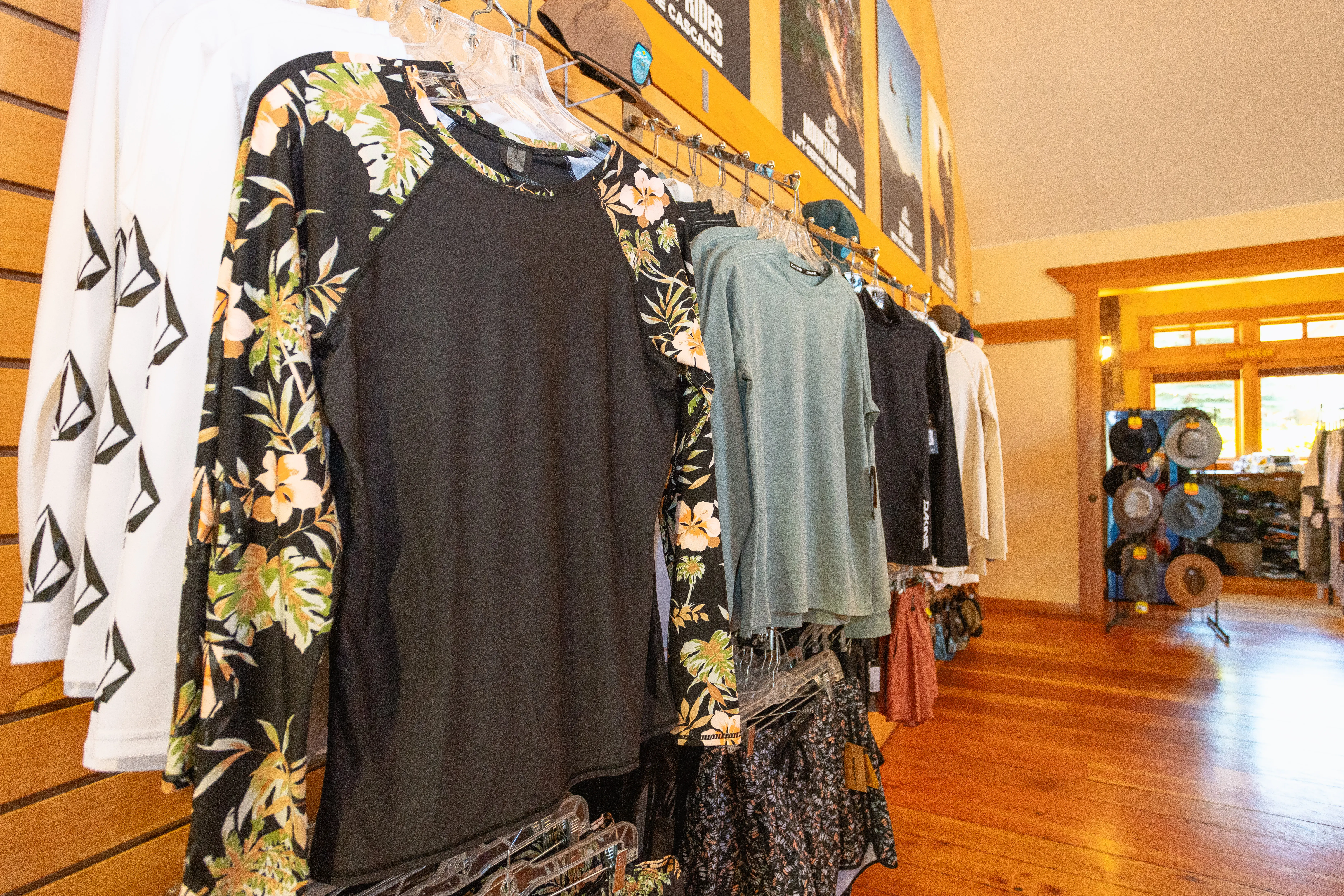 Assorted long-sleeve shirts and hats displayed on racks in the Sun Country Tours retail shop, perfect for outdoor adventures and rafting trips.